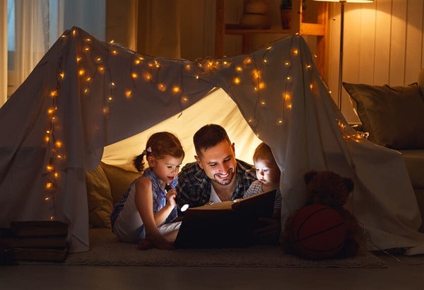 father reading with his kids under flashlight